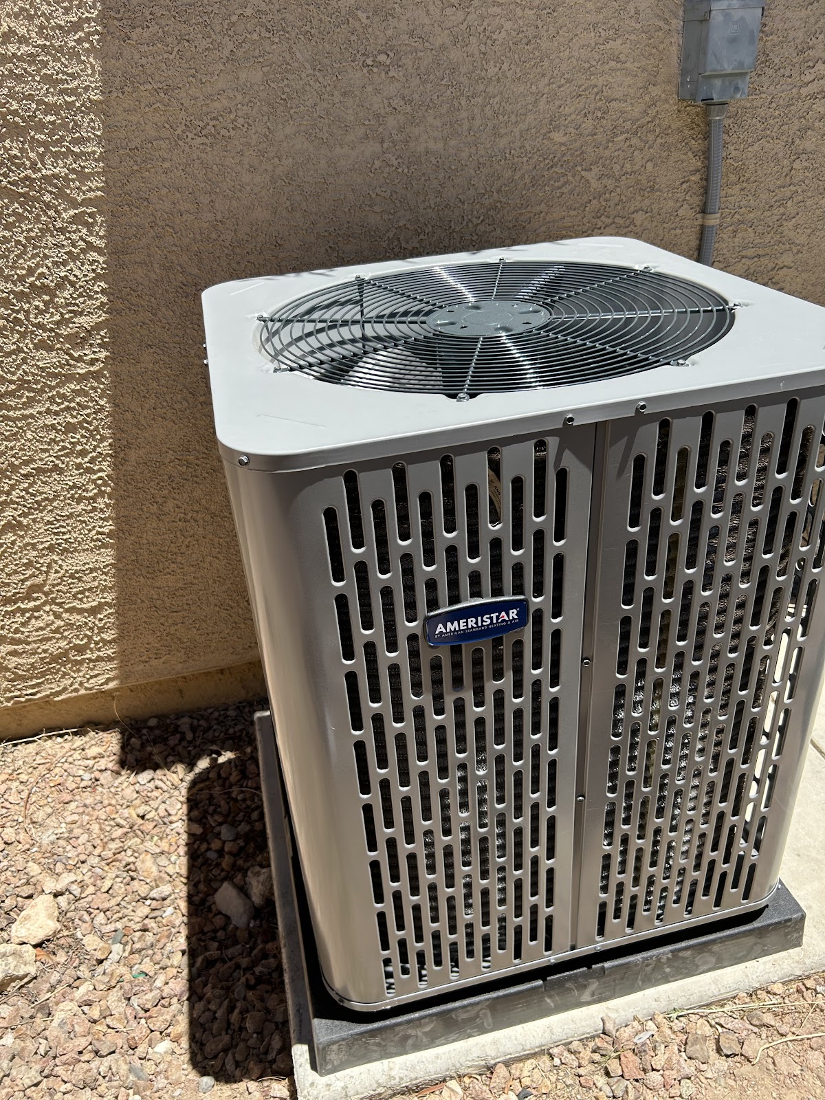 Freshly installed Ameristar AC condenser unit beside stucco wall
